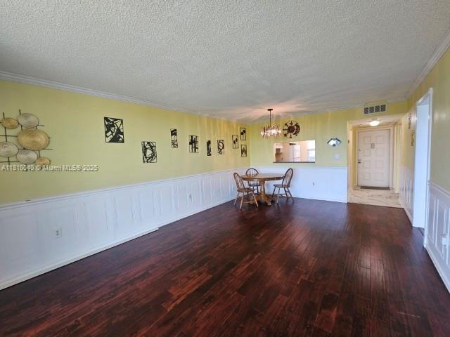 900 Colony Point Cir Unit 505, Pembroke Pines, FL 33026 - unfurnished dining area featuring a chandelier, a textured ceiling, hardwood / wood-style flooring, a wainscoted wall, and crown molding