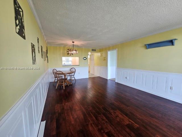 900 Colony Point Cir Unit 505, Pembroke Pines, FL 33026 - spare room featuring a textured ceiling, a chandelier, wainscoting, wood finished floors, and crown molding