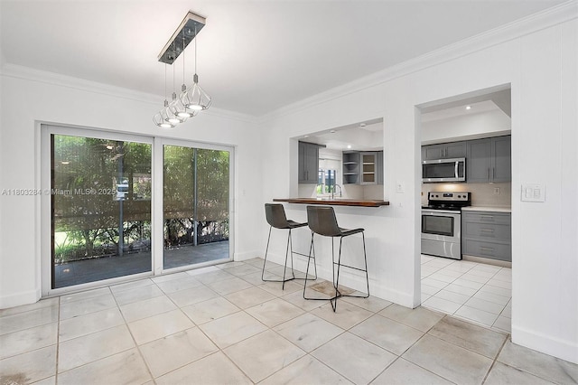 1884 Galleon St Unit 1, North Bay Village, FL 33141 - kitchen featuring stainless steel appliances, gray cabinets, light tile patterned floors, ornamental molding, and a breakfast bar