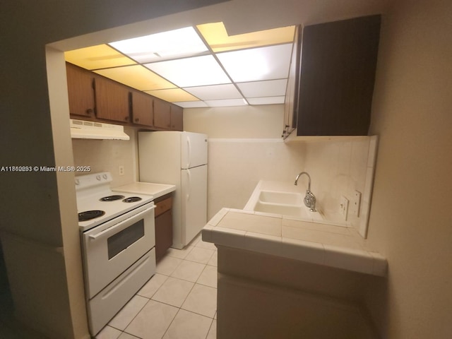 1500 N Congress Ave Unit B53, West Palm Beach, FL 33401 - kitchen featuring under cabinet range hood, white appliances, tile counters, a sink, and a paneled ceiling