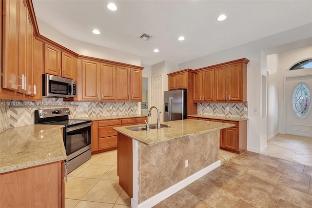 9212 Short Chip Cir, Port St Lucie, FL 34986 - kitchen featuring stainless steel appliances, a sink, backsplash, light stone counters, and a center island with sink