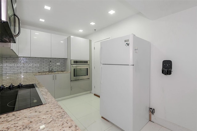 6039 Collins Ave Unit 307, Miami Beach, FL 33140 - kitchen featuring black appliances, decorative backsplash, a sink, white cabinets, and light stone countertops