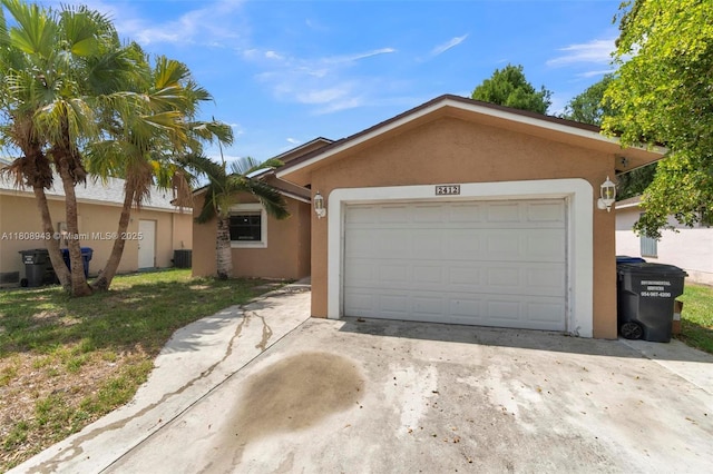 2412 Raleigh St, Hollywood, FL 33020 - single story home with concrete driveway, stucco siding, central air condition unit, and a garage