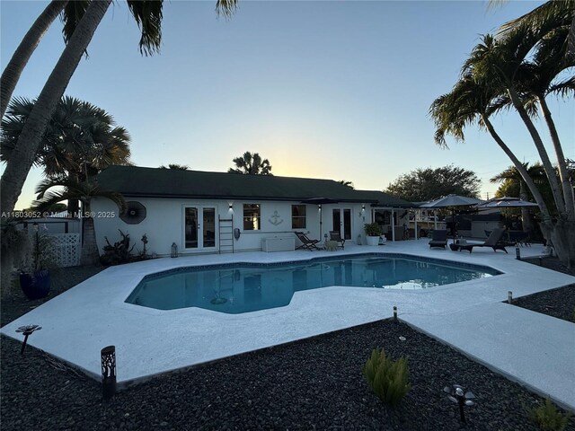 15223 SW 152nd Ave, Miami, FL 33187 - pool at dusk featuring french doors, a patio, and an outdoor pool
