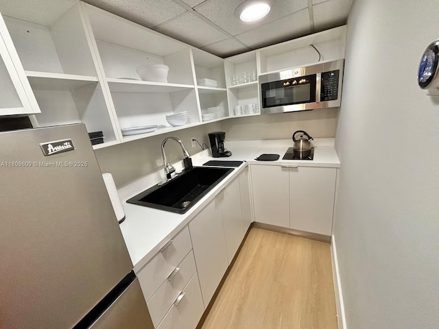 750 Collins Ave Unit 206, Miami Beach, FL 33139 - kitchen featuring open shelves, a sink, stainless steel appliances, light wood finished floors, and white cabinets