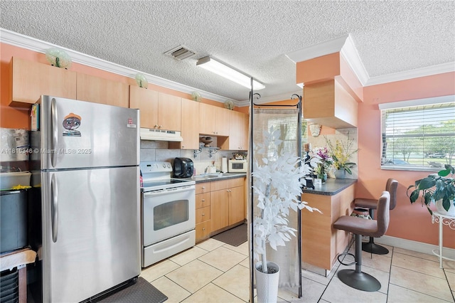 5829 Taylor St, Hollywood, FL 33021 - kitchen with white appliances, under cabinet range hood, light brown cabinetry, ornamental molding, and a sink