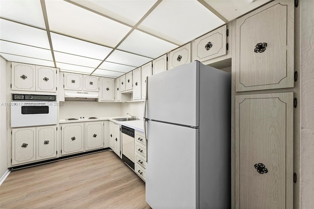 19380 Collins Ave Unit 317, Sunny Isles Beach, FL 33160 - kitchen featuring white appliances, under cabinet range hood, light wood finished floors, a sink, and a drop ceiling