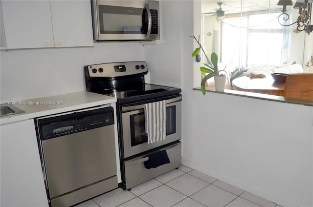 13499 Biscayne Blvd Unit 702, North Miami, FL 33181 - kitchen featuring appliances with stainless steel finishes, white cabinets, light countertops, light tile patterned floors, and baseboards