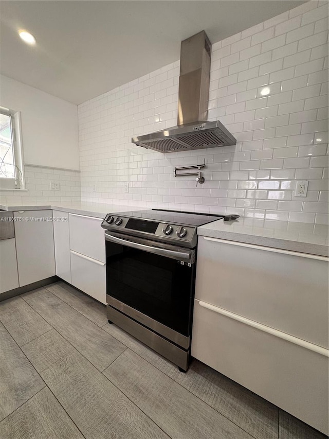 501 SW 18th St, Pompano Beach, FL 33060 - kitchen featuring stainless steel electric range oven, wall chimney range hood, tasteful backsplash, white cabinets, and light countertops