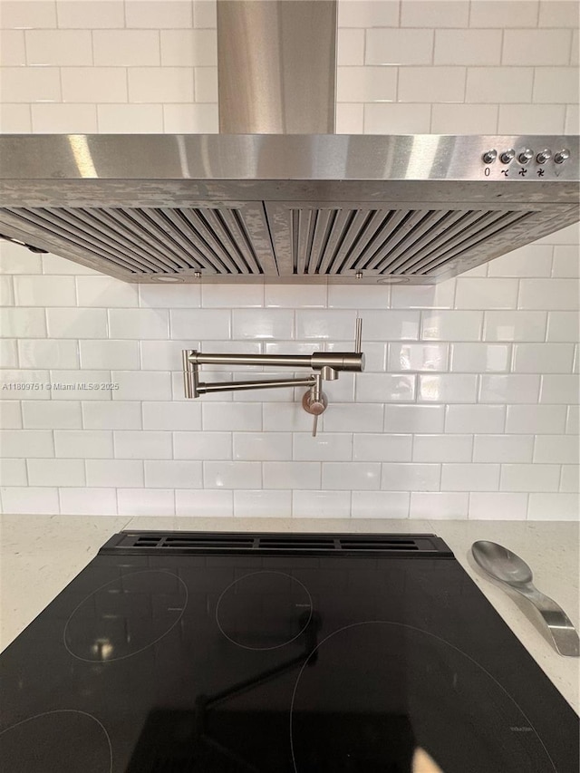 501 SW 18th St, Pompano Beach, FL 33060 - kitchen view of pot filler, wall chimney range hood, decorative backsplash, stove, and light stone countertops