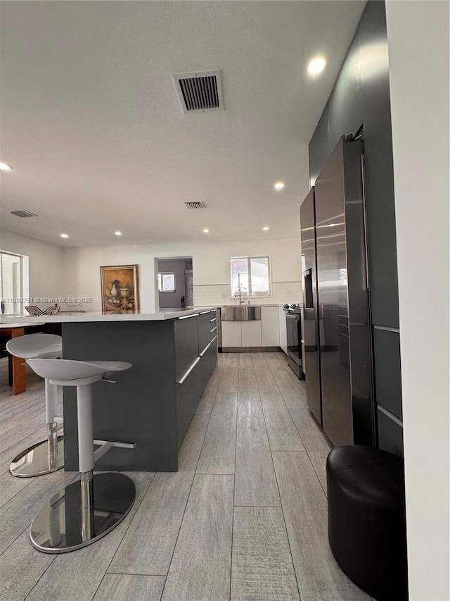 501 SW 18th St, Pompano Beach, FL 33060 - kitchen with modern cabinets, a center island, stainless steel electric stove, light wood finished floors, and light countertops