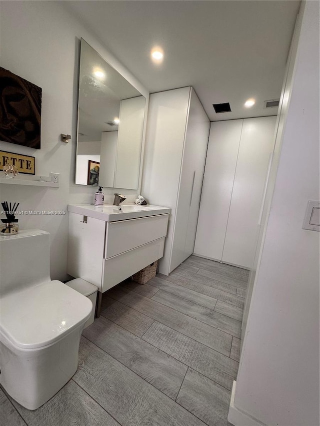 501 SW 18th St, Pompano Beach, FL 33060 - bathroom featuring vanity, toilet, wood finished floors, and recessed lighting