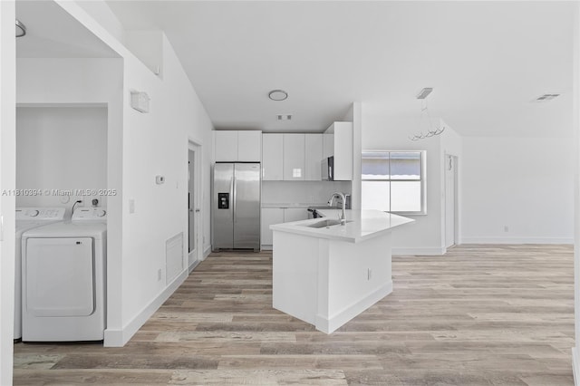 7572 NW 3rd St, Plantation, FL 33317 - kitchen featuring stainless steel appliances, washer and dryer, a sink, white cabinetry, and light wood-style flooring