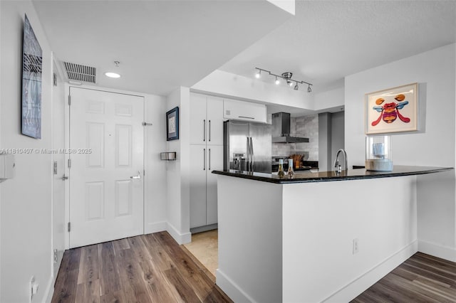 3232 SW 22nd Ter Unit 1106, Miami, FL 33145 - kitchen featuring appliances with stainless steel finishes, a peninsula, dark wood-style flooring, wall chimney exhaust hood, and white cabinetry