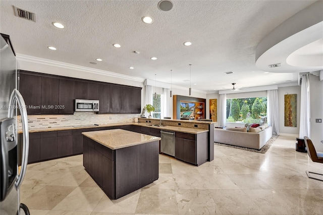 11356 Canyon Maple Blvd, Davie, FL 33330 - kitchen with stainless steel appliances, a center island, a sink, crown molding, and dark brown cabinetry