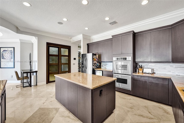 11356 Canyon Maple Blvd, Davie, FL 33330 - kitchen with stainless steel appliances, ornamental molding, a kitchen island, dark brown cabinetry, and decorative backsplash