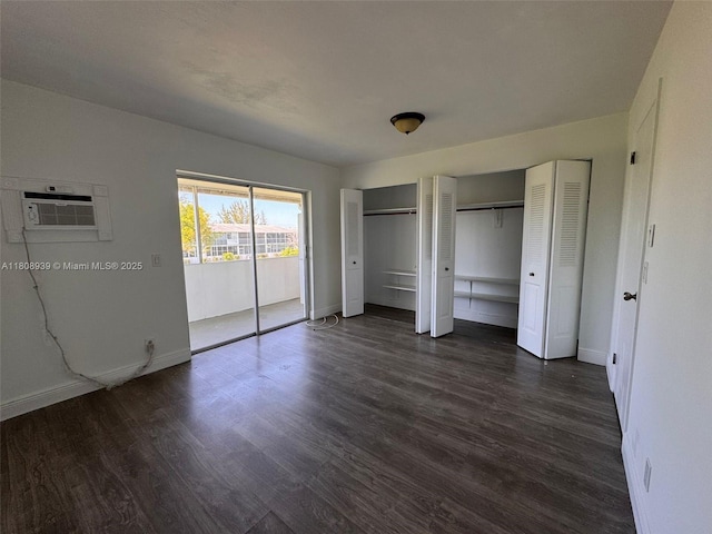 218 Windsor J Unit 218, West Palm Beach, FL 33417 - unfurnished bedroom featuring a wall unit AC, baseboards, dark wood-style floors, and two closets