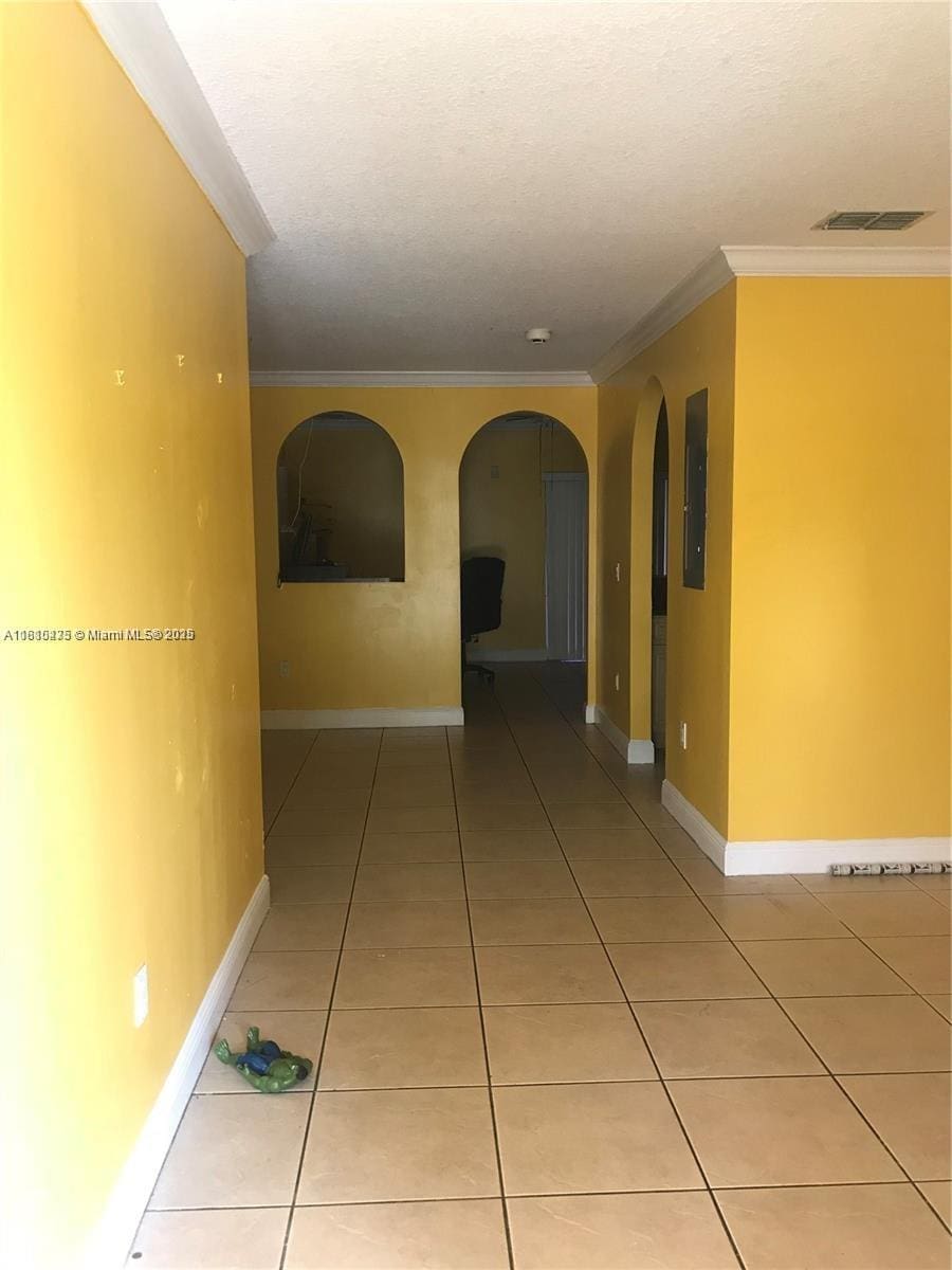 12912 NE 7th Ave, North Miami, FL 33161 - corridor with light tile patterned floors, electric panel, arched walkways, crown molding, and a textured ceiling