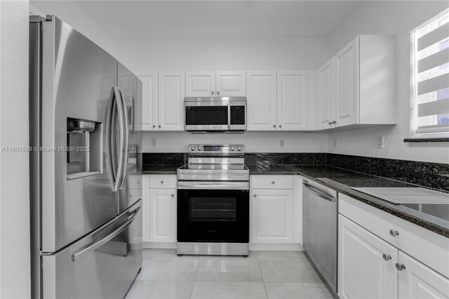 9285 SW 220th Ter, Cutler Bay, FL 33190 - kitchen featuring appliances with stainless steel finishes, white cabinetry, light tile patterned floors, and dark stone counters
