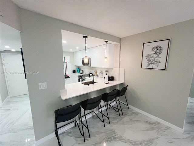 3725 S Ocean Dr Unit 425, Hollywood, FL 33019 - kitchen with light marble finish flooring, a sink, a kitchen bar, white cabinets, and baseboards
