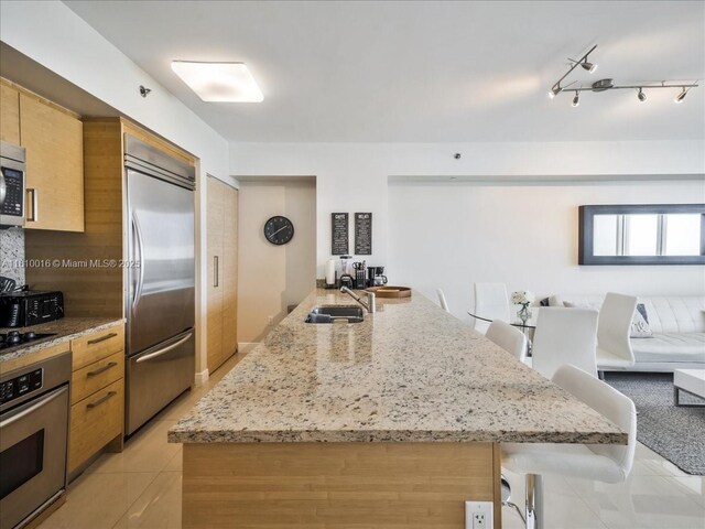 1830 S Ocean Dr Unit 5009, Hallandale Beach, FL 33009 - kitchen with appliances with stainless steel finishes, a sink, light tile patterned floors, light stone countertops, and a breakfast bar