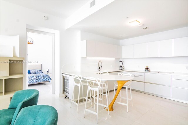 16901 Collins Ave Unit 2504, Sunny Isles Beach, FL 33160 - kitchen featuring a kitchen bar, white cabinets, and light countertops