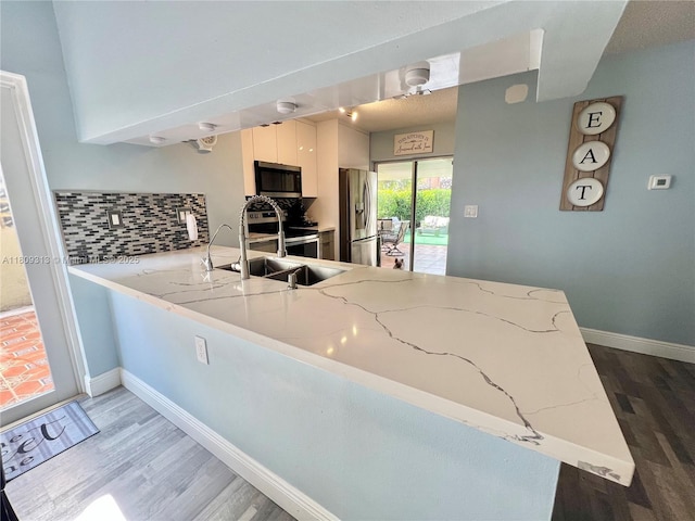 15333 SW 40th Ter, Miami, FL 33185 - kitchen featuring appliances with stainless steel finishes, wood finished floors, a peninsula, tasteful backsplash, and a sink