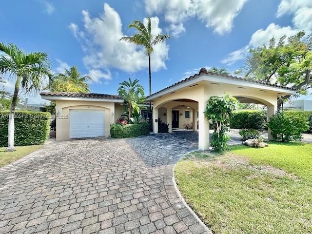 1945 N Hibiscus Dr, North Miami, FL 33181 - view of front of home featuring stucco siding, decorative driveway, a garage, and a front yard