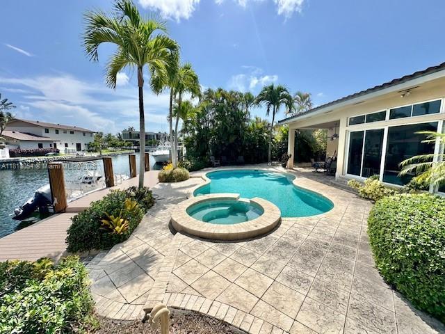 1945 N Hibiscus Dr, North Miami, FL 33181 - view of pool featuring a patio, a pool with connected hot tub, and a water view