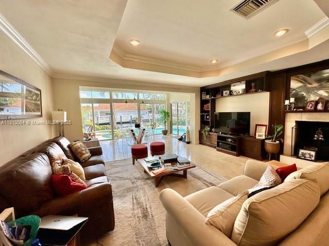 1945 N Hibiscus Dr, North Miami, FL 33181 - living room featuring a raised ceiling, ornamental molding, recessed lighting, and built in shelves
