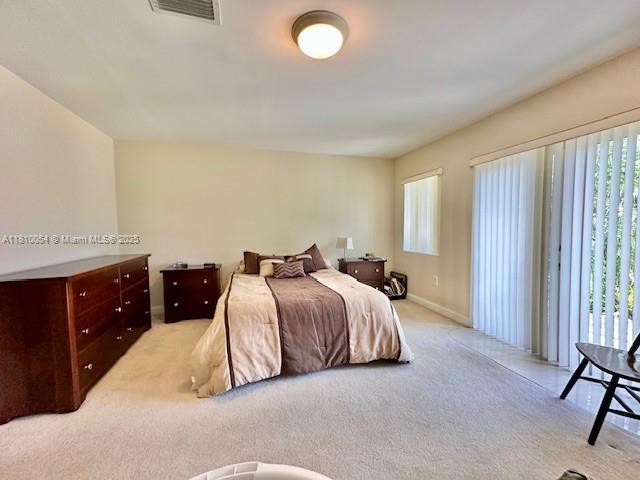 1945 N Hibiscus Dr, North Miami, FL 33181 - bedroom featuring light carpet, baseboards, and access to exterior
