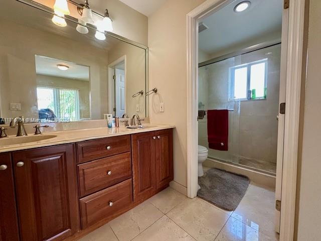 1945 N Hibiscus Dr, North Miami, FL 33181 - bathroom with double vanity, toilet, a shower stall, and tile patterned floors