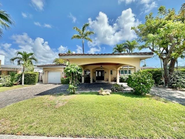 1945 N Hibiscus Dr, North Miami, FL 33181 - mediterranean / spanish-style house with a front lawn, decorative driveway, stucco siding, and an attached garage