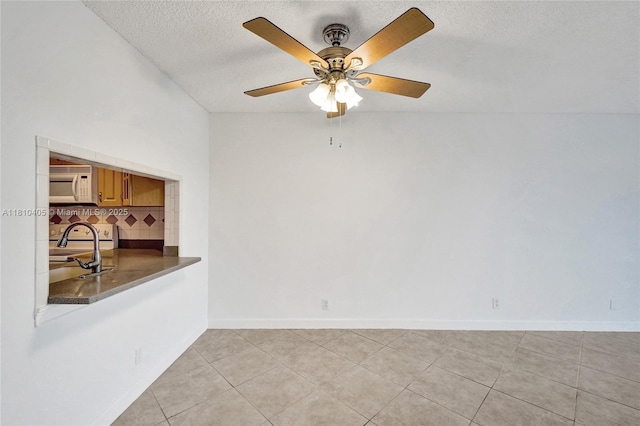 9450 Poinciana Pl Unit 212, Davie, FL 33324 - empty room featuring a sink, light tile patterned floors, a textured ceiling, ceiling fan, and baseboards