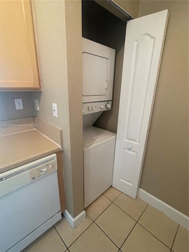 6001 SW 70th St Unit 535, South Miami, FL 33143 - laundry area with stacked washer and clothes dryer, light tile patterned floors, and baseboards