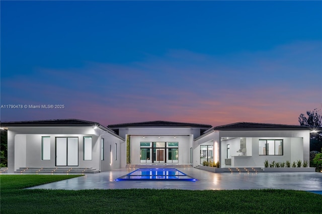 12331 SW 2nd St, Plantation, FL 33325 - back of property at dusk featuring an outdoor pool, a lawn, stucco siding, and a patio area