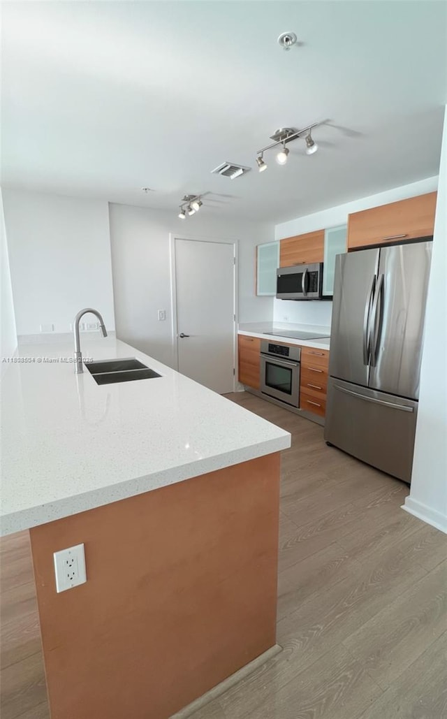 3301 NE 1st Ave Unit H2304, Miami, FL 33137 - kitchen featuring appliances with stainless steel finishes, a sink, brown cabinets, light wood-style floors, and light stone countertops