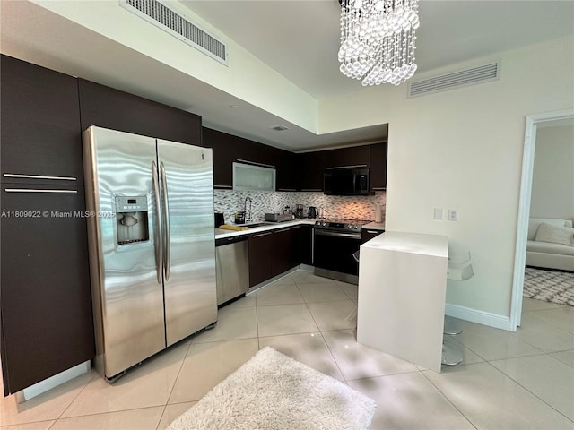 950 Brickell Bay Dr Unit 2607, Miami, FL 33131 - kitchen featuring stainless steel appliances, light tile patterned flooring, a chandelier, decorative backsplash, and light countertops