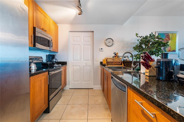 1300 Ponce De Leon Blvd Unit 705, Coral Gables, FL 33134 - kitchen featuring appliances with stainless steel finishes, a sink, light tile patterned floors, dark stone counters, and brown cabinets
