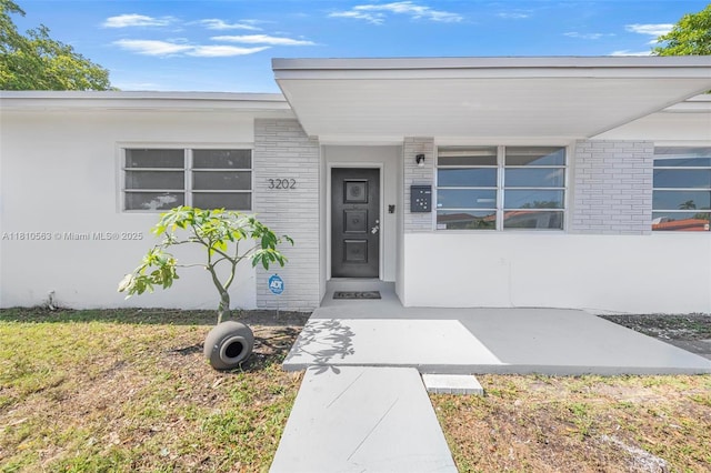 3202 SW 3rd St, Miami, FL 33135 - view of exterior entry featuring brick siding and a lawn