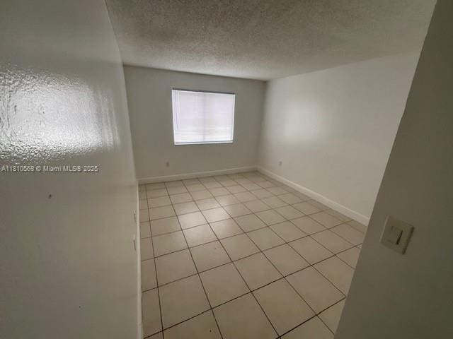 15221 SW 80th St Unit 201, Miami, FL 33193 - empty room featuring light tile patterned floors, a textured ceiling, and baseboards