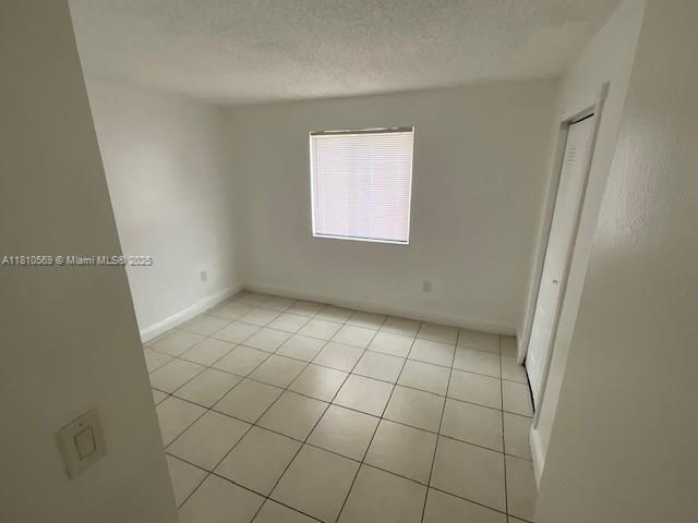 15221 SW 80th St Unit 201, Miami, FL 33193 - spare room featuring a textured ceiling, baseboards, and light tile patterned flooring