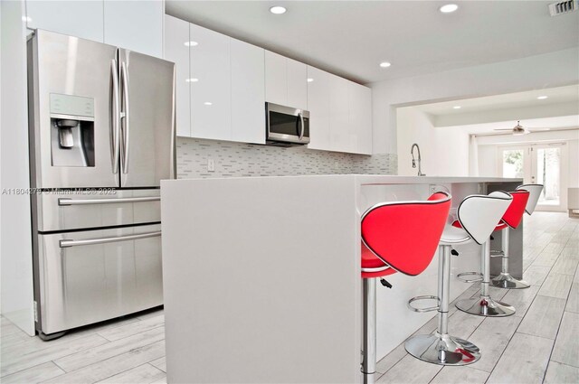 1328 NW 93rd Ter, Coral Springs, FL 33071 - kitchen featuring appliances with stainless steel finishes, white cabinetry, wood tiled floors, recessed lighting, and ceiling fan