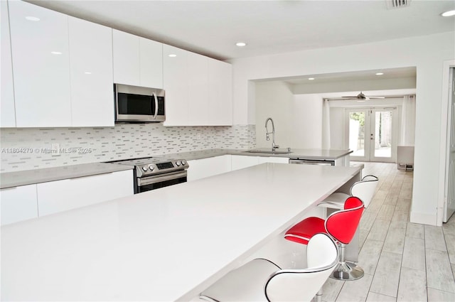 1328 NW 93rd Ter, Coral Springs, FL 33071 - kitchen with stainless steel appliances, a sink, a breakfast bar area, white cabinetry, and a peninsula