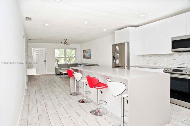 1328 NW 93rd Ter, Coral Springs, FL 33071 - kitchen with appliances with stainless steel finishes, a kitchen breakfast bar, open floor plan, tasteful backsplash, and white cabinetry