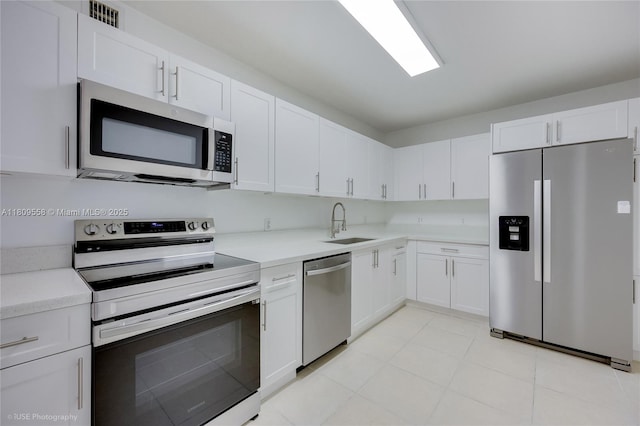 401 69th St Unit 708, Miami Beach, FL 33141 - kitchen with stainless steel appliances, light countertops, white cabinetry, and light tile patterned floors