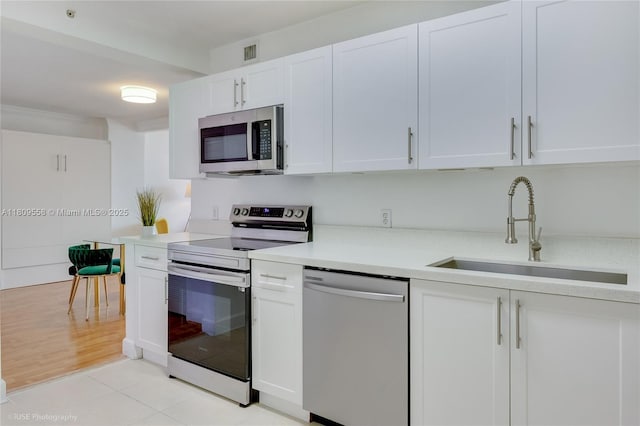 401 69th St Unit 708, Miami Beach, FL 33141 - kitchen featuring stainless steel appliances, light countertops, white cabinets, and light tile patterned floors