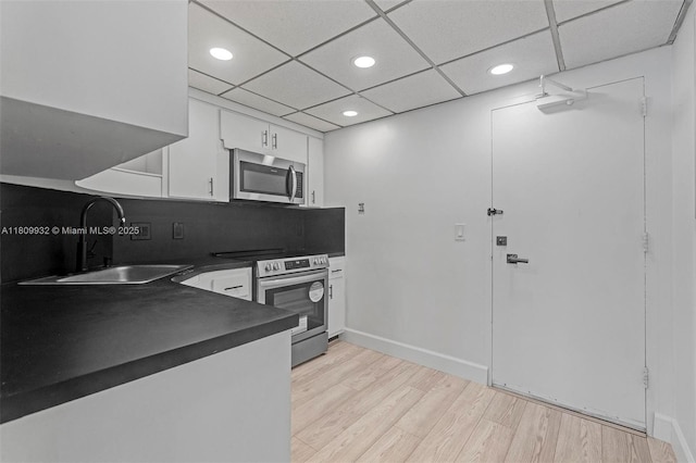 3700 Galt Ocean Dr Unit 1408, Fort Lauderdale, FL 33308 - kitchen featuring appliances with stainless steel finishes, dark countertops, a sink, white cabinets, and light wood-type flooring