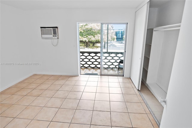 15610 NE 6th Ave Unit 22B, Miami, FL 33162 - unfurnished bedroom featuring access to exterior, light tile patterned floors, a closet, a wall unit AC, and baseboards