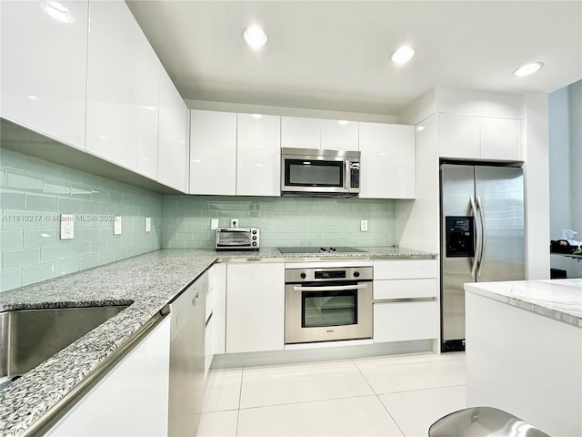 1060 Brickell Ave Unit 801, Miami, FL 33131 - kitchen featuring appliances with stainless steel finishes, modern cabinets, white cabinetry, and light stone counters